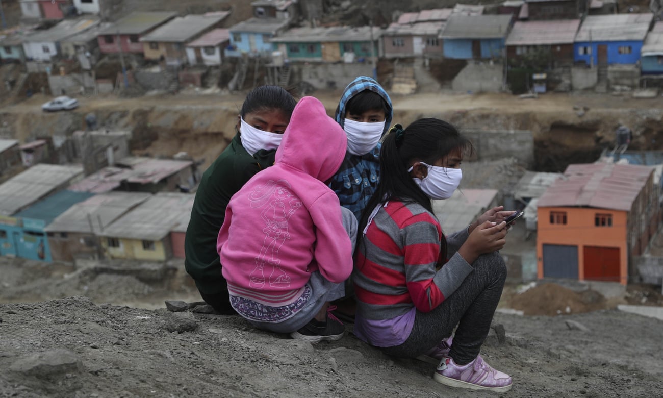Children wearing masks sit on a hill in Puente Piedra shantytown on the outskirts of Lima.