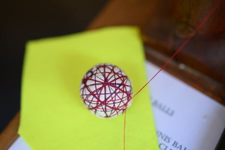Ball of red string wrapped around cotton sitting on a yellow cloth
