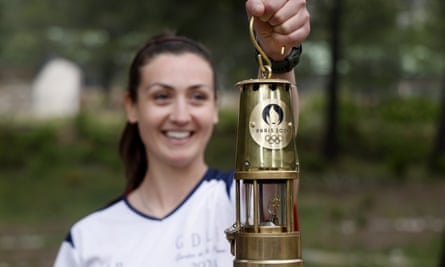 Smiling young woman holds receptacle containing the Olympic flame.