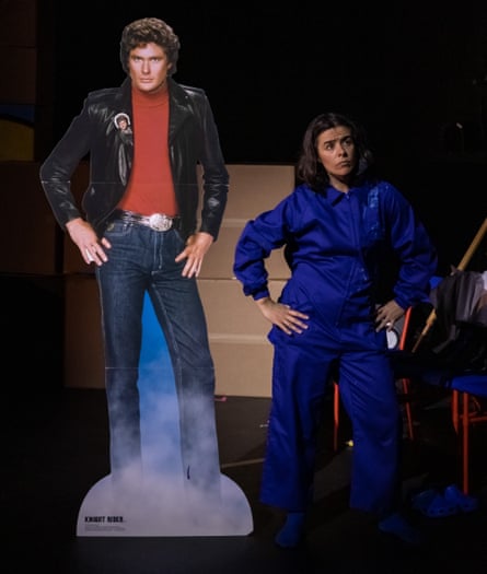 Alice Roots wearing a blue jumpsuit stands next to a cardboard lifesize image of David Hasselhoff as Knight Rider copying his stance