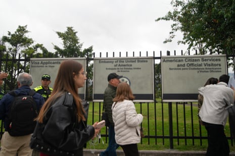 Black gate with three signs on it and people walking in front
