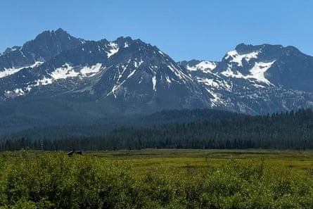 Snow-dotted mountains guidelines against a bluish entity earlier a wide swath of greenish land.