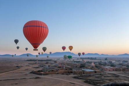 Hot air balloons rising above a small Moroccan village.