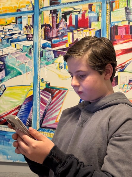 a boy looks down at his phone