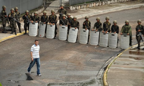 A pedestrian walks past a row of soldiers near the presidential palace following a coup d’etat that saw President Manuel Zelaya ousted in Tegucigalpa on 28 June 2009.