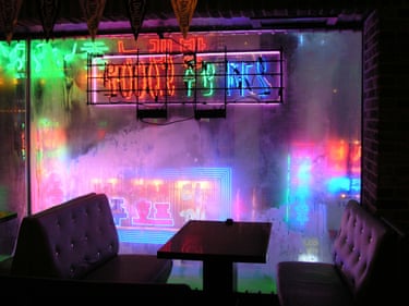Empty booth seating in Seoul sits before a foggy window lit by colourful neon signs