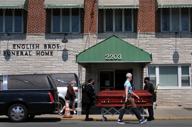 Pedestrians walk past the English Bros Funeral Home as a casket is unloaded in the Brooklyn borough of New York.