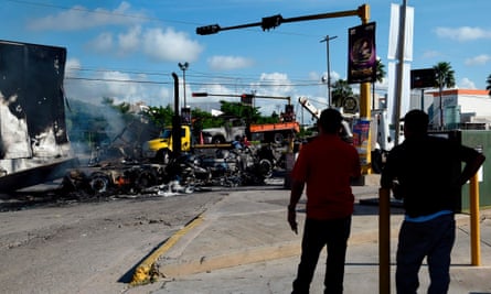 Men look at burnt vehicles after heavily armed gunmen waged an all-out battle against Mexican security forces in Culiacan, Sinaloa state, Mexico, on Friday.