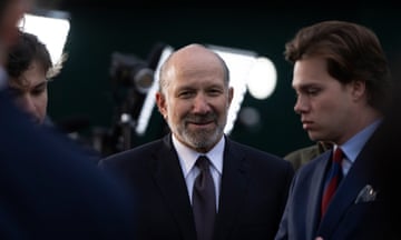 man wearing black suit and tie stands in between to two other men