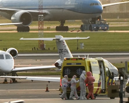 A person in a hazmat suit is escorted to an ambulance from a medical aircraft carrying evacuees from the MV Hondius at Schiphol airport, Amsterdam.