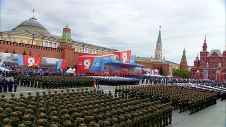 Russian service members stand in uniform lines in Moscow's Red Square under a cloudy gray sky.