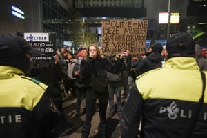 A protester holding a placard in Dutch confronts riot police.