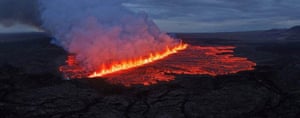 A long crack in the Earth’s surface is spewing bright orange lava and thick smoke from a fissure after a volcanic eruption in Reykjanes, Iceland