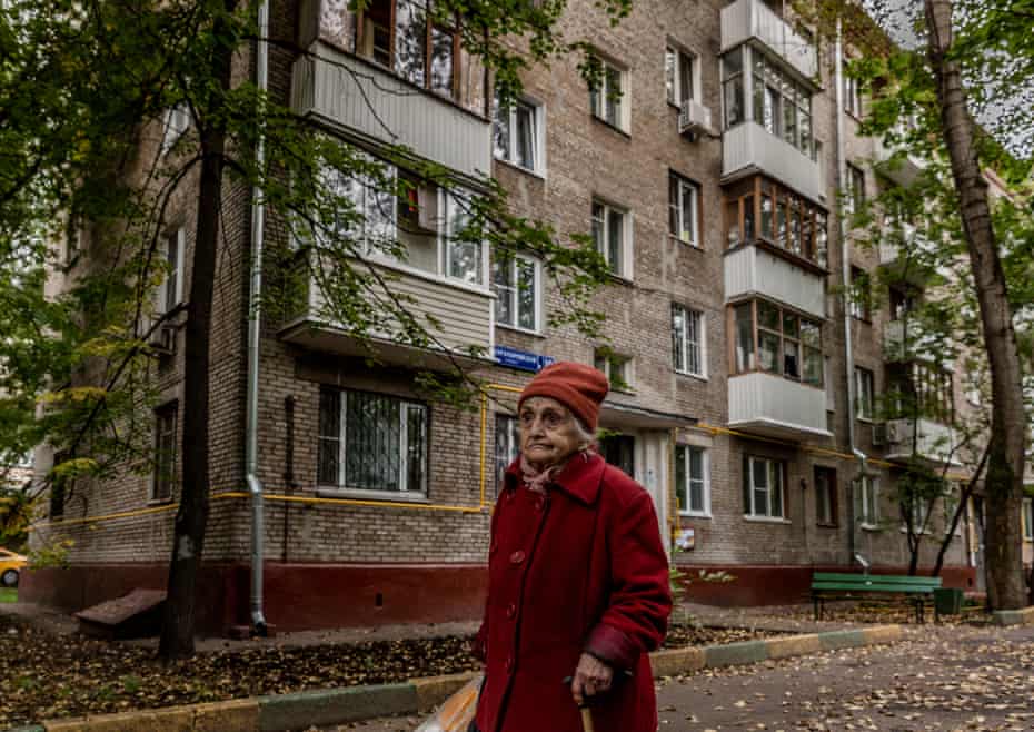 An elderly resident walks past a Khrushchevka apartment block