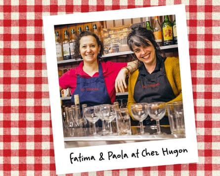 An instant photo of two women behind a bar, against a red gingham background.