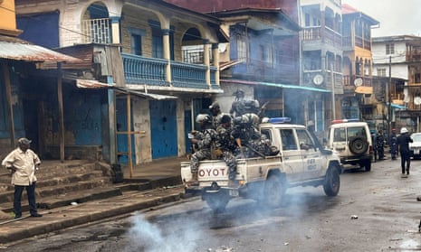 Riot police patrol as they pass smoke rising from a roadblock during anti-government protests in Freetown, Sierra Leone.