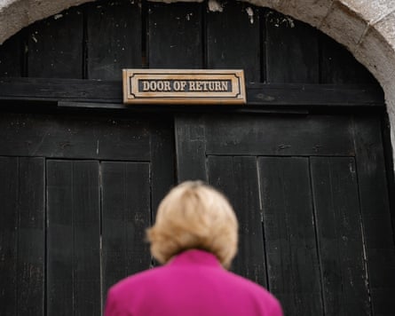 The archbishop of Canterbury faces a large wooden door with a sign above it saying ‘Door of Return’