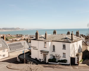 A white early Victorian house with the sea in the background