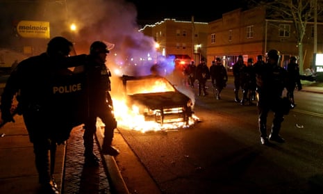 Police officers walk by a burning police car in Ferguson, Missouri.