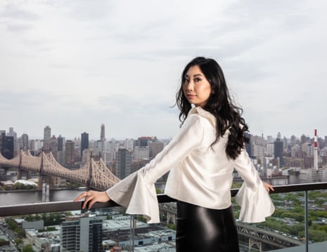 Gene technology entrepreneur Cathy Tie, standing on a balcony looking back to camera, New York behind her