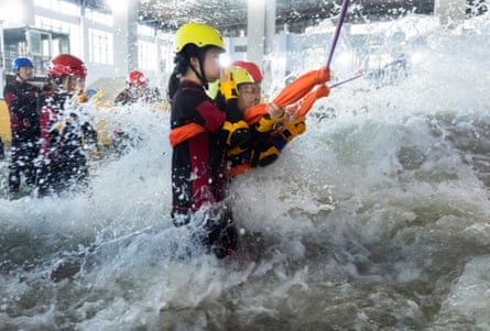 Participants brace for surging water in a flash flood simulator at the Lvxing centre in Hangzhou.