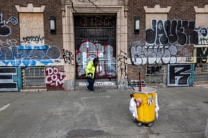 A city worker picks up trash next to graffiti on 4th Avenue. 