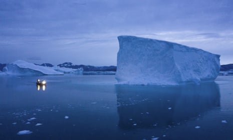 A boat navigates at night next to large icebergs in eastern Greenland