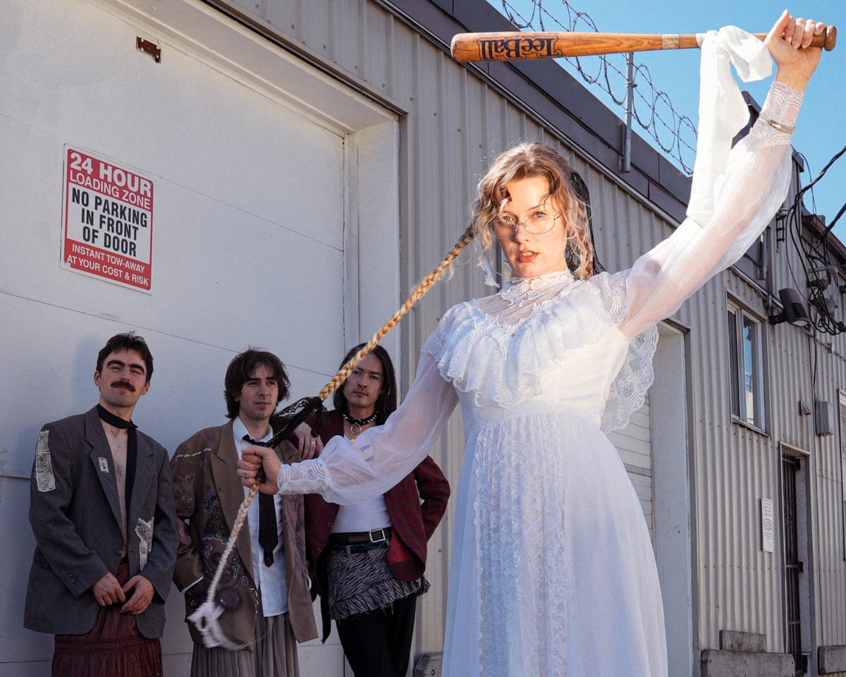 The members of Piss outside a warehouse, with singer Taylor Zantingh wearing a white nightgown and wielding a baseball bat