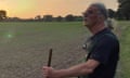 Bryn Austin holding a stick as he looks across a field at sunset