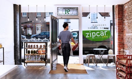 Homem levando caixa de produtos da loja para a van Zipcar
