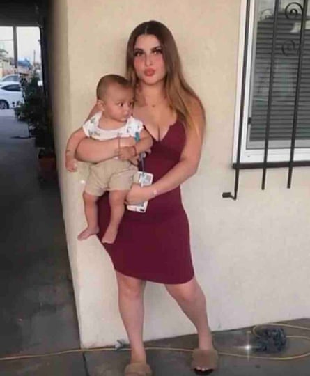 A woman in a red dress holding a baby posing for a photograph