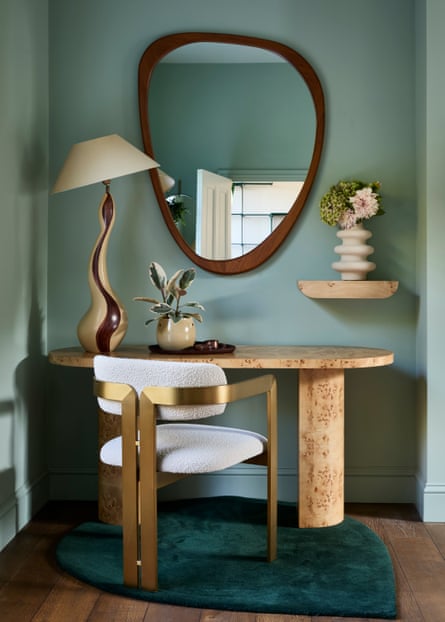 A dressing table with gold upholstered chair, plants, asymmetric mirror and curvy lamp