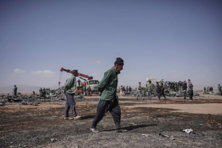 Two people at site with wreckage and more people in background