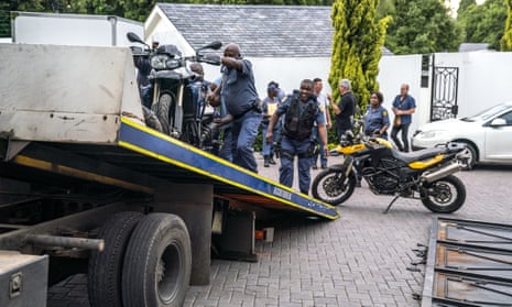 Police officers load motorcycles on to a truck in a residential area