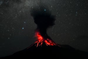 A volcano erupts against a night sky