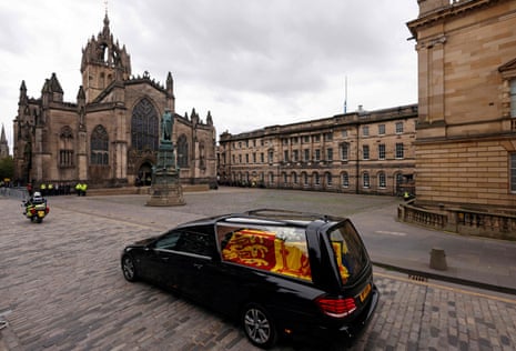 The hearse carrying the coffin of Queen Elizabeth II, draped in the Royal Standard of Scotland, is driven past St Giles' Cathedral in Edinburgh, where the Queen will be taken tomorrow.