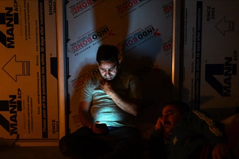 A man checks his mobile phone as he takes shelter in the basement of a building during shelling in Poonch district