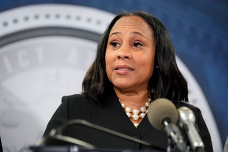 A woman wearing black speaks into a microphone and looks ahead
