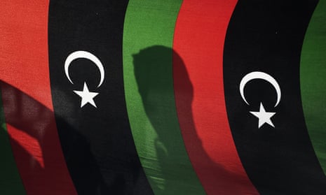 The shadow of a protester is cast on Libyan flags