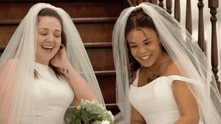 Two women in wedding dresses and veils, laughing