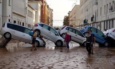 Residents walk past piled up cars following deadly floods in Valencia’s De La Torre neighbourhood, south of Valencia, eastern Spain, on October 30, 2024. Floods triggered by torrential rains in Spain’s eastern Valencia region has left at least 70 people dead, rescue services said on October 30. (Photo by Manaure QUINTERO / AFP) (Photo by MANAURE QUINTERO/AFP via Getty Images)
