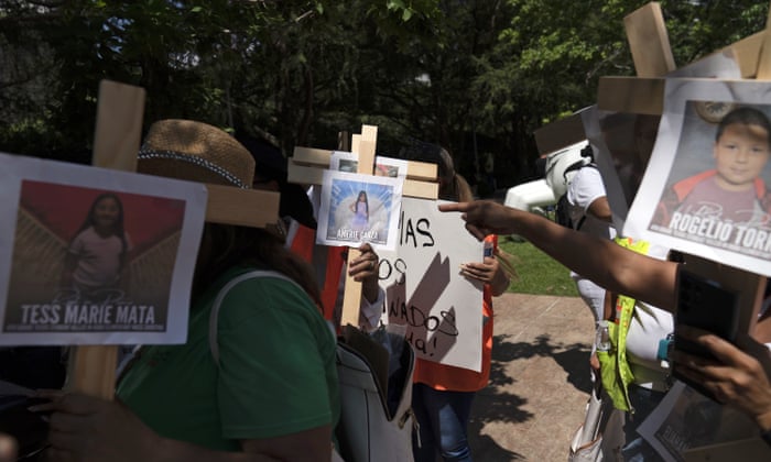 Protesters carry crosses with photos of victims of the shooting in Uvalde.