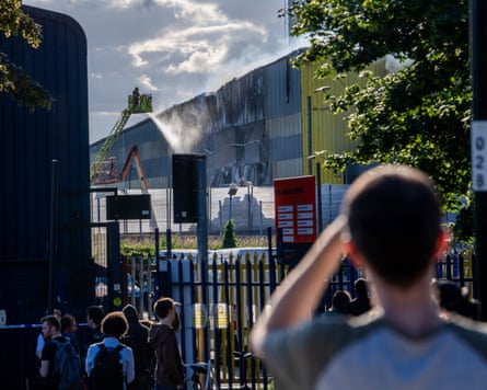 People watching the firefighting from behind a fence