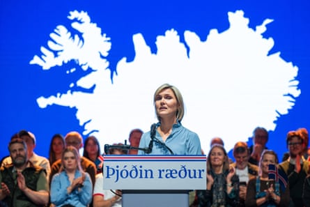 Kristrún Frostadóttir stands at a podium in front of a bright background that shows the outline of the island of Iceland