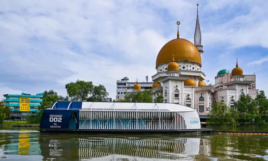 A barge moves along a river with the dome of a mosque in the background