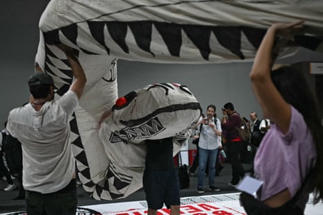 People hold a huge cobra doll during a demonstration demanding climate justice and more protection of indigenous territories at the Blue Zone of the COP30
