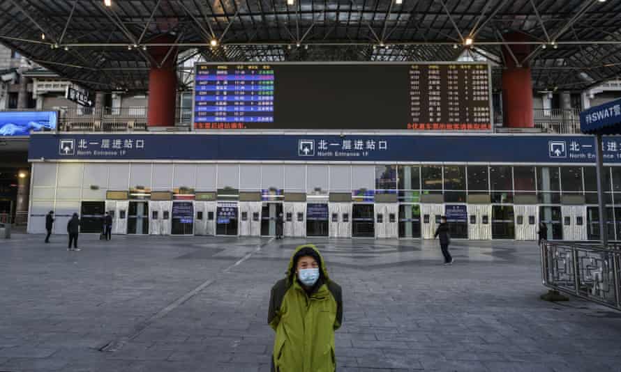 A Chinese man stands outside a main entrance at the nearly empty Beijing West Railway Station.