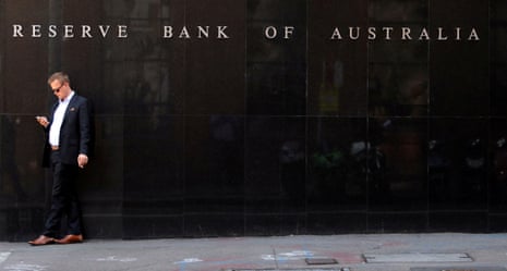 A man smokes and looks at his phone outside the Reserve Bank of Australia