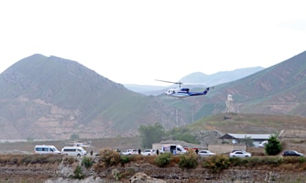 A helicopter takes off against a background of mountains