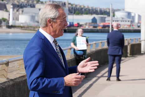 Nigel Farage in Aberdeen today, where he was holding a press conference, with a protester behind him.